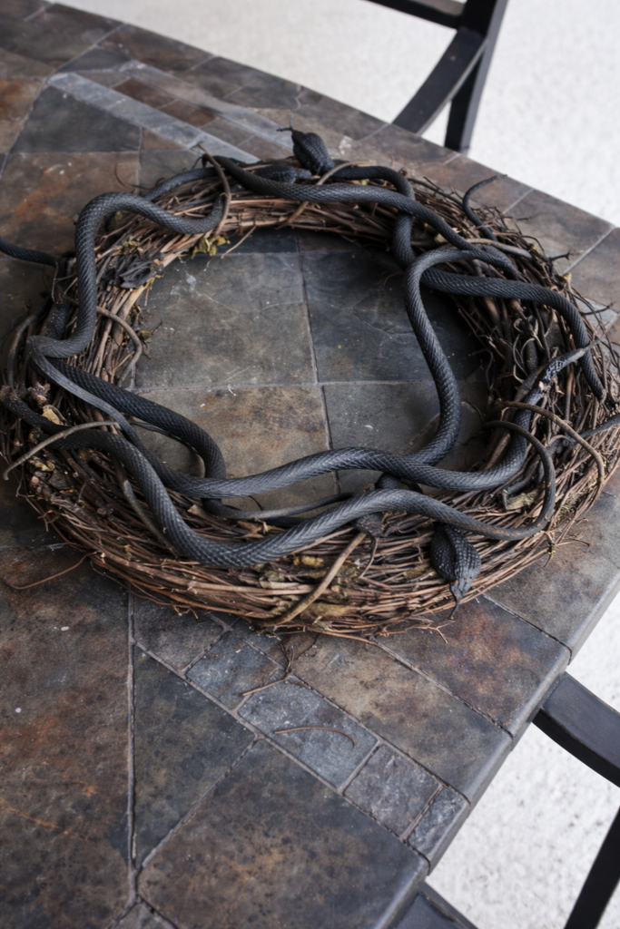 Black rubber snakes woven into a grapevine wreath base while making a DIY Halloween snake nest wreath.