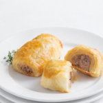 Homemade Irish sausage rolls with flaky puff pastry and seasoned pork filling on a white plate