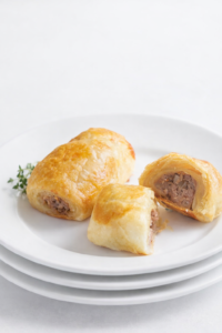 Homemade Irish sausage rolls with flaky puff pastry and seasoned pork filling on a white plate