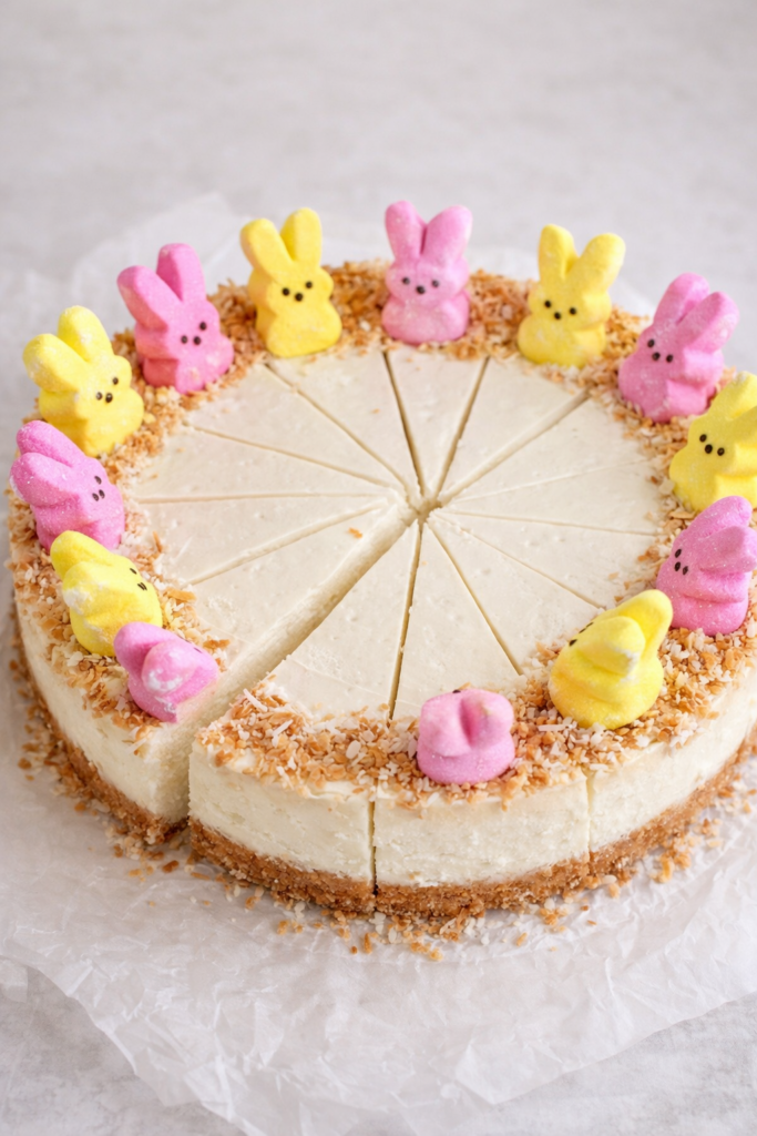 Easter cheesecake sitting on parchment paper decorated with toasted coconut around the edge and pastel Peeps