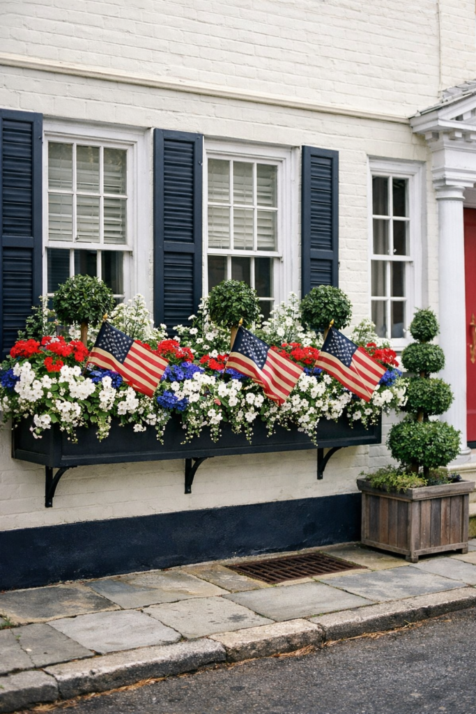 Coastal Americana window box with red, white, and blue flowers and American flags on a classic white brick townhouse
