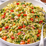 Warm mustard cabbage salad with red bell pepper, red onion, parsley, and whole-grain mustard dressing in a white serving bowl.