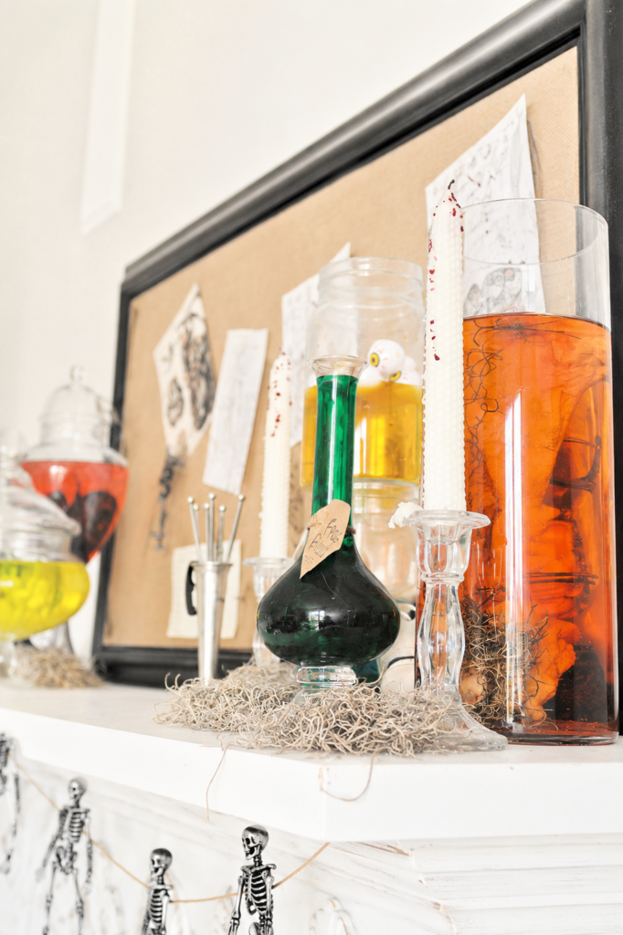 Close-up of a bright vintage-inspired Halloween mantel featuring colorful potion bottles, specimen jars, candles, anatomy sketches, and spooky mad scientist laboratory decor.