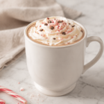 Homemade peppermint white chocolate mocha topped with whipped cream, crushed candy cane and chocolate curls in a white mug