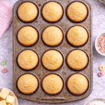 Unfrosted cereal milk cupcakes baked in a used muffin pan shown in a flat lay view on a marble countertop