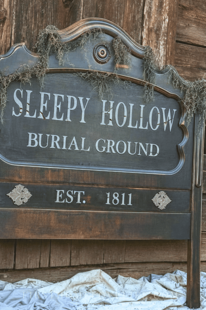 Thrifted headboard transformed into a Sleepy Hollow Burial Ground Halloween sign leaning against a rustic barn