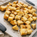 homemade garlic croutons baking on sheet pan on marble countertop