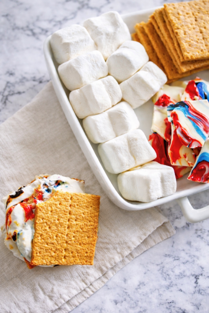 Easy red, white, and blue patriotic s’mores with swirled chocolate on marble background and linen cloth