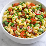 Garlicky BLT macaroni salad with bacon, tomatoes, lettuce, and creamy garlic mayo dressing in a white bowl on a light marble background