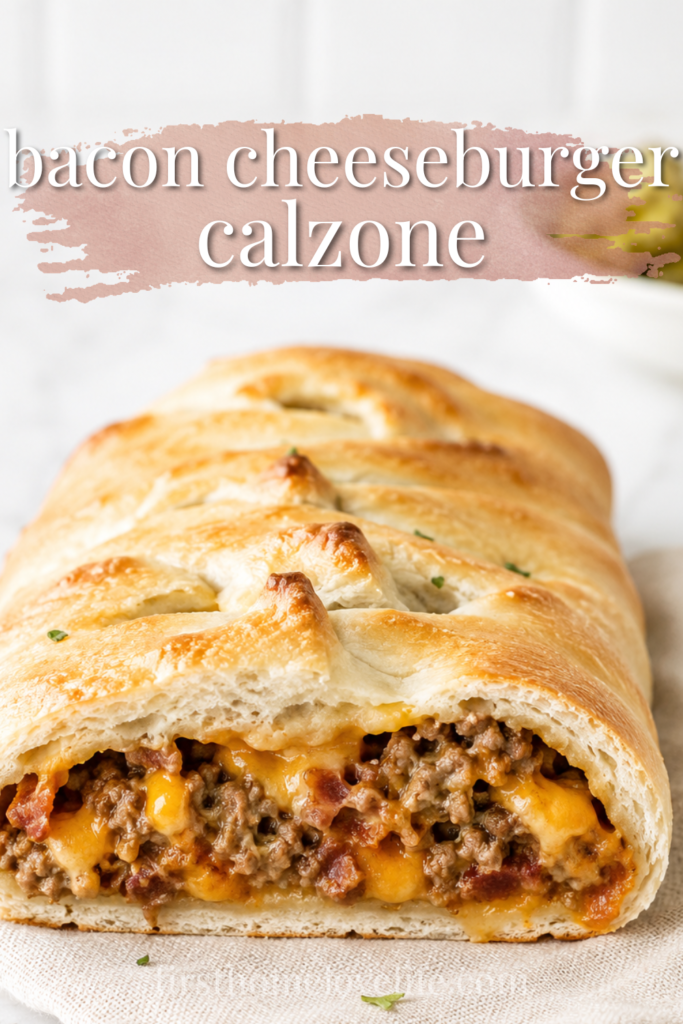 Golden bacon cheeseburger calzone filled with seasoned ground beef, crispy bacon, and melted cheddar cheese on a marble countertop with a neutral linen cloth.