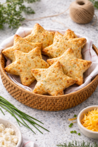 Golden cheddar chive star-shaped biscuits in a wicker basket on a granite countertop