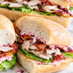 Leftover turkey sandwich on a crusty hoagie roll with cranberry mayo, crispy bacon, smoked Gouda cheese, and romaine lettuce.