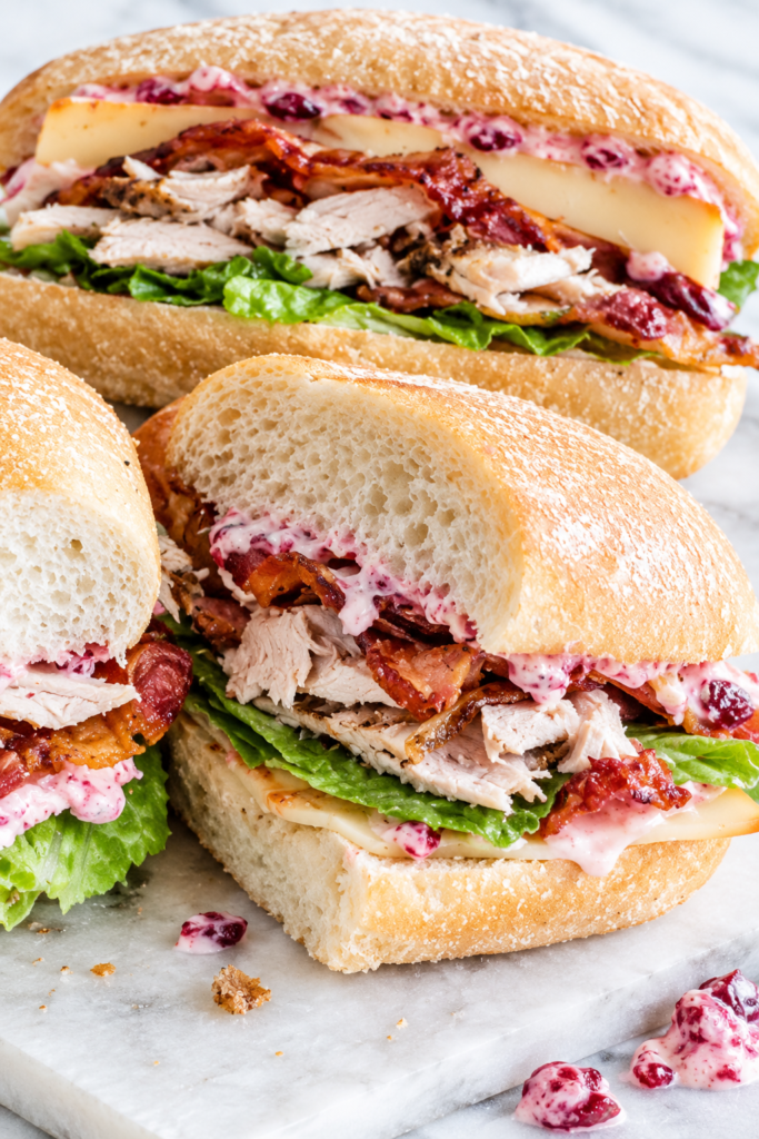 Leftover turkey sandwich on a crusty hoagie roll with cranberry mayo, crispy bacon, smoked Gouda cheese, and romaine lettuce.