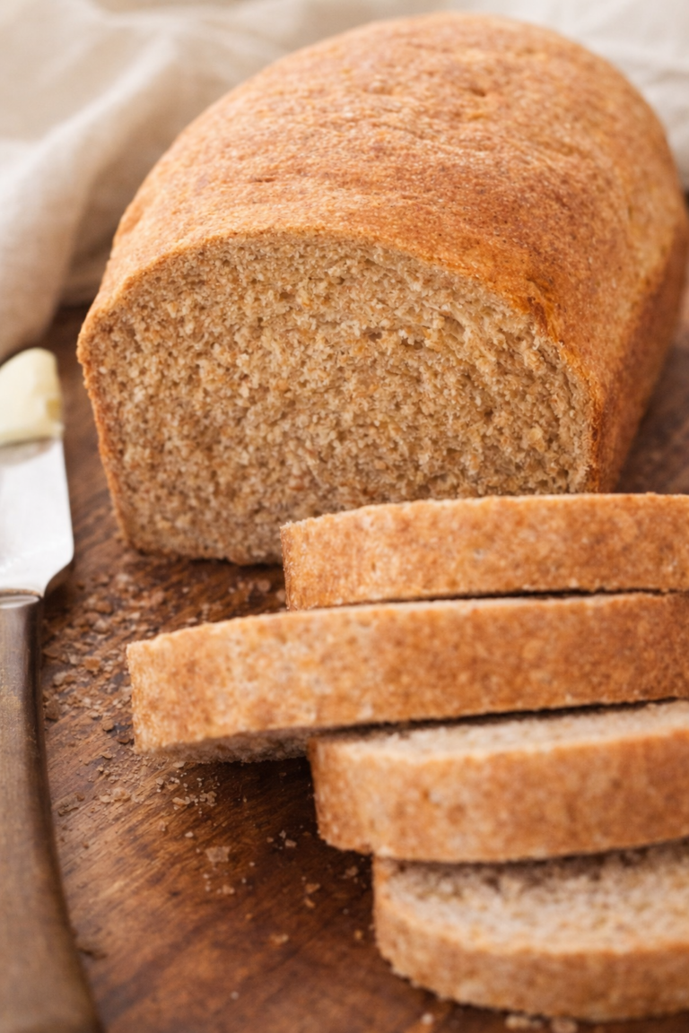 Soft homemade whole wheat bread loaf sliced on a wooden cutting board with golden crust and fluffy interior