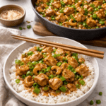 Chicken with cashews cooking in a skillet and served over white rice in a bowl with chopsticks