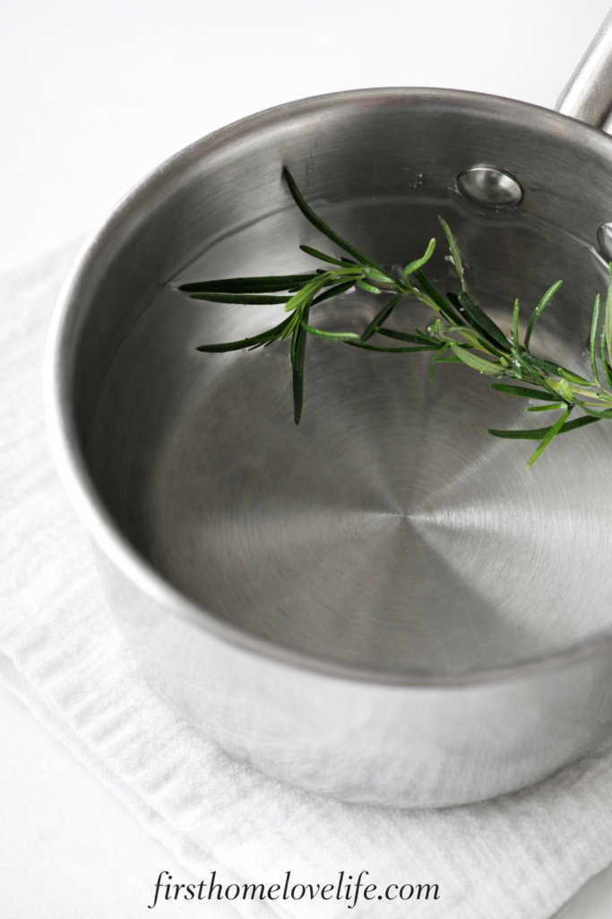 Fresh rosemary steeping in hot water in a saucepan for homemade dog shampoo recipe