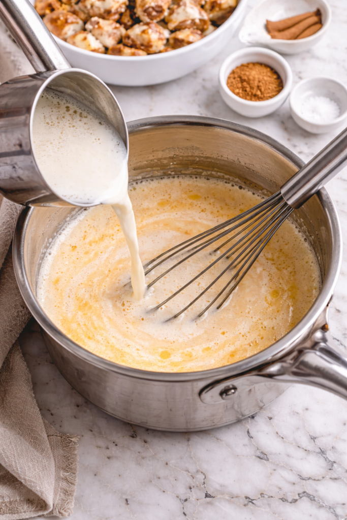 Whisking warm vanilla custard for slow cooker cinnamon roll bread pudding in a saucepan