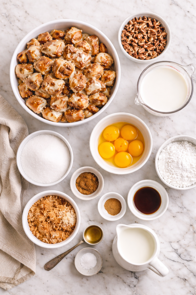 Flat lay of ingredients for slow cooker cinnamon roll bread pudding including cinnamon rolls, eggs, cream, sugar, and pecans