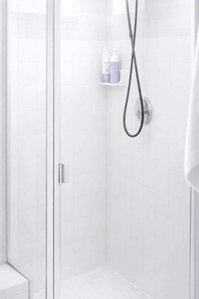 Bright white tile shower with clear glass door after removing soap scum and hard water stains.