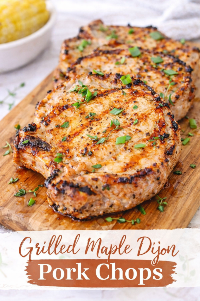 Juicy grilled maple Dijon pork chops with caramelized edges, garnished with herbs on a wooden board.