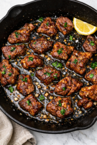 Garlic miso butter steak bites seared in a cast iron skillet with fresh parsley and lemon.
