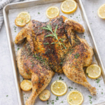 Lemon thyme spatchcock chicken roasted on a sheet pan with crispy golden skin and fresh herbs