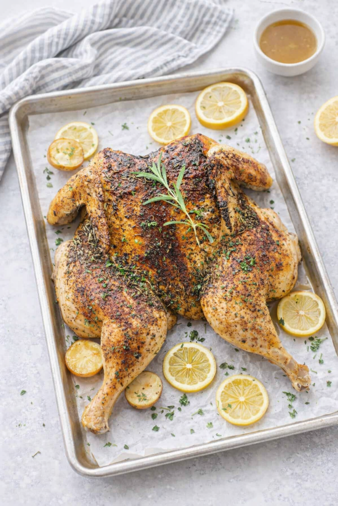 Lemon thyme spatchcock chicken roasted on a sheet pan with crispy golden skin and fresh herbs