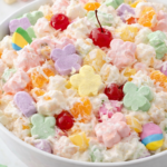 Close up of creamy Easter ambrosia salad with pastel bunny marshmallows, mandarin oranges, pineapple, coconut, and maraschino cherries