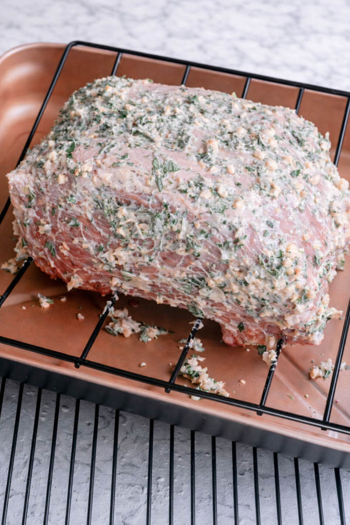 prime rib roast coated with garlic herb butter on roasting rack