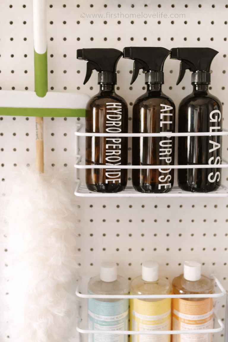 cleaning command center pegboard with labeled spray bottles for glass cleaner, all purpose cleaner and hydrogen peroxide