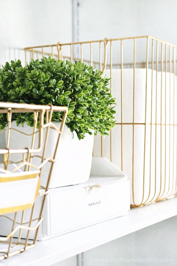 Laundry room shelf organization ideas using gold wire baskets, simple storage boxes, and decor for a clean and organized laundry room.