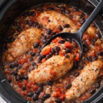 Southwestern chicken with black beans cooking in a slow cooker with roasted red peppers and tomatoes