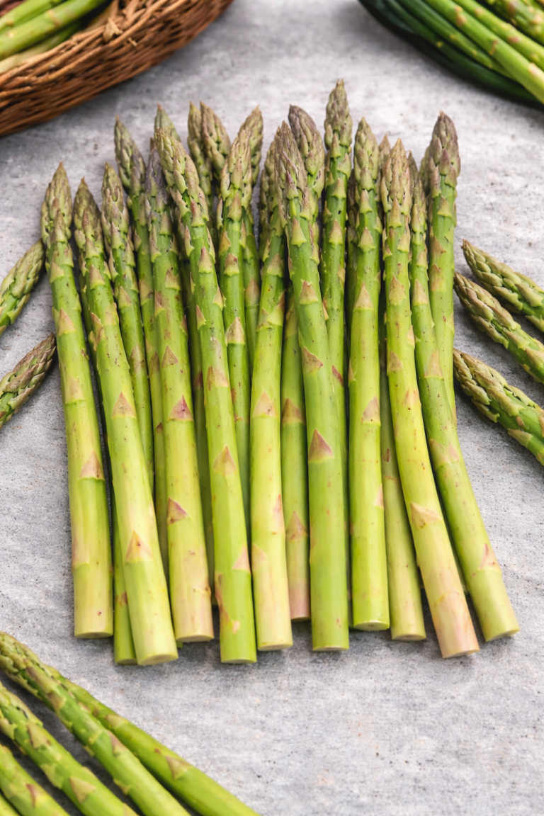 Fresh green asparagus spears neatly arranged in a clean flat lay on a light gray surface.
