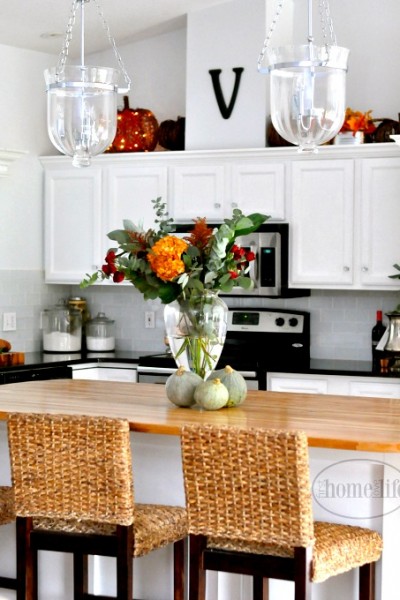White kitchen cabinets with butcher block island. Beautiful white kitchen with subway tiles decorated for fall. Via First Home Love Life www.firsthomelovelife.com