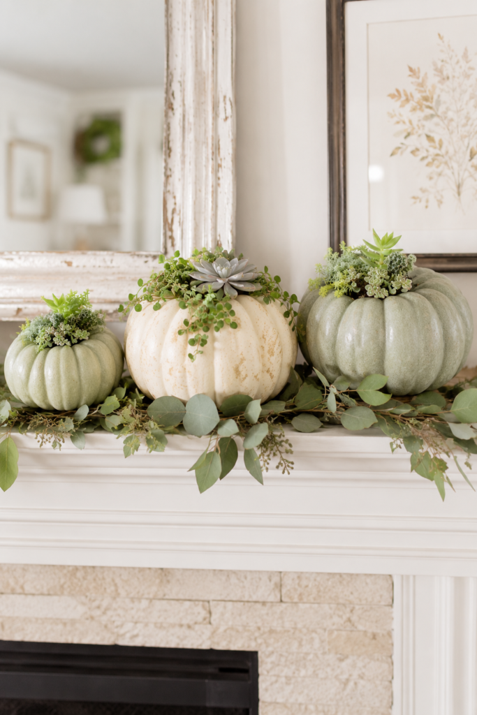 Elegant succulent pumpkins displayed on a white fireplace mantel with eucalyptus garland for classy fall home decor.