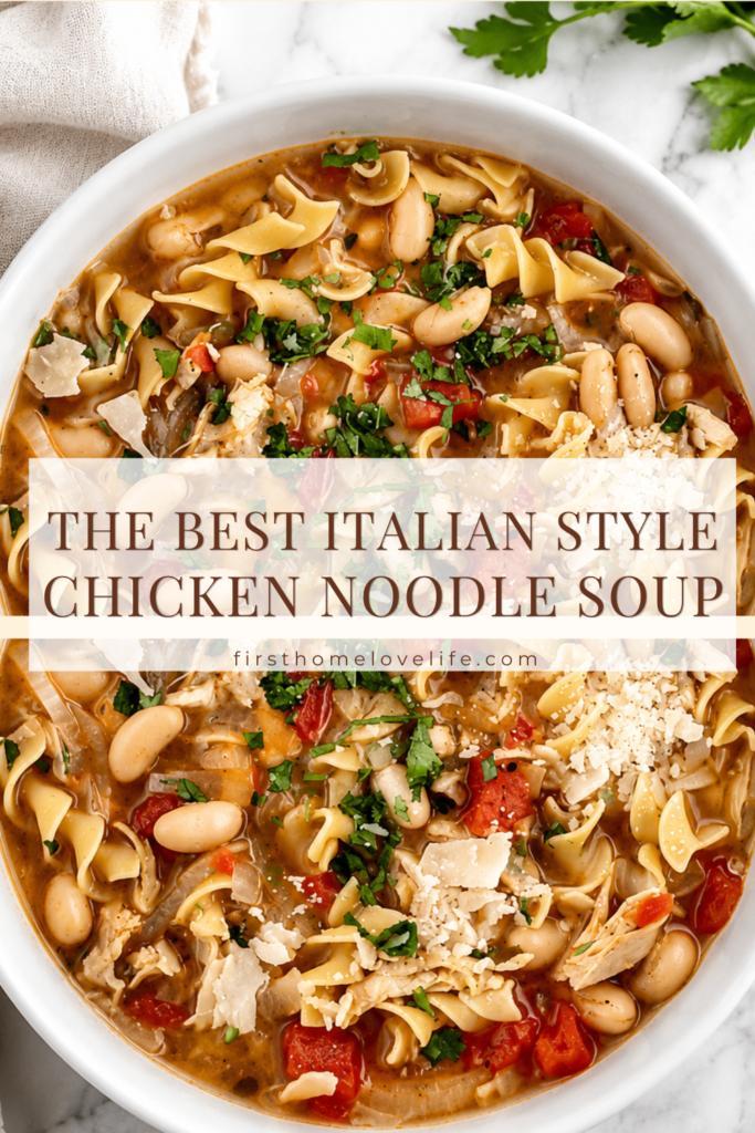 Bowl of homemade Italian chicken noodle soup with shredded chicken, egg noodles, cannellini beans, tomatoes, Parmesan cheese, and fresh parsley in a white bowl on a marble countertop.