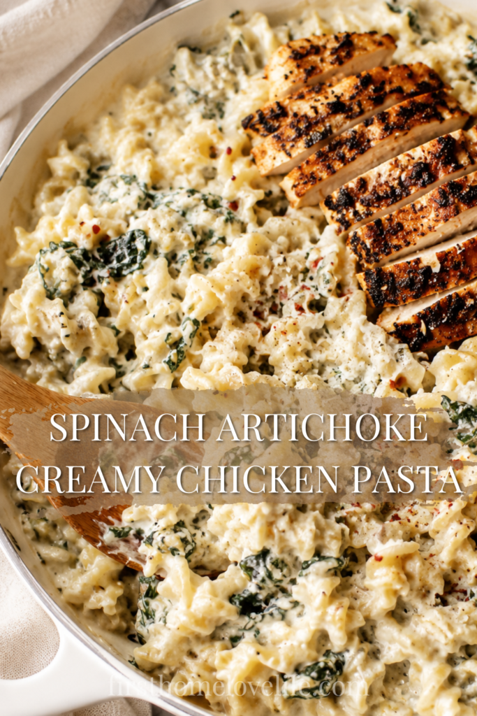 Creamy spinach artichoke chicken pasta in a white skillet topped with sliced blackened chicken and Parmesan cheese on a marble countertop.
