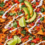 loaded Doritos nachos with ground beef melted cheese avocado sour cream tomatoes and cilantro
