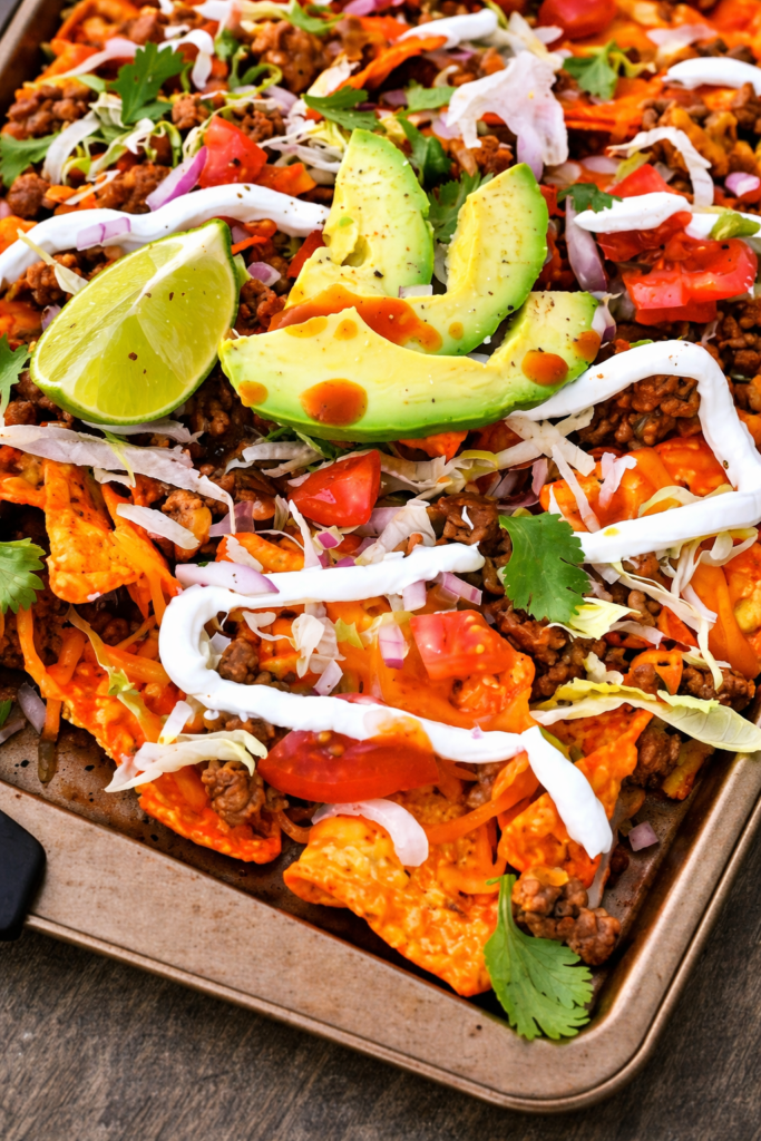 close up Doritos nachos with ground beef melted cheese avocado lime sour cream and fresh toppings