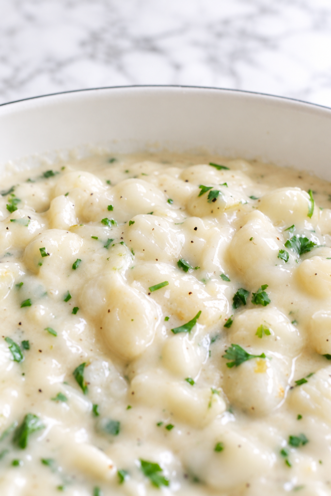 Creamed pearl onions in a smooth garlic herb sauce in a white serving dish