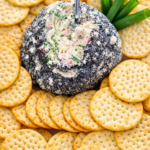 Smokey ham crack dip cheese ball coated in poppy seeds and surrounded by buttery round crackers