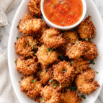 Crispy homemade coconut fried shrimp served on a white platter with sweet chili apricot dipping sauce.
