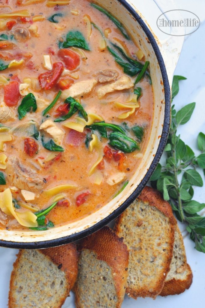 Creamy Tuscan chicken noodle soup is the perfect cold weather meal! Loaded with chicken, noodles, sun dried tomatoes and spinach in a creamy garlic tomato broth! via firsthomelovelife.com