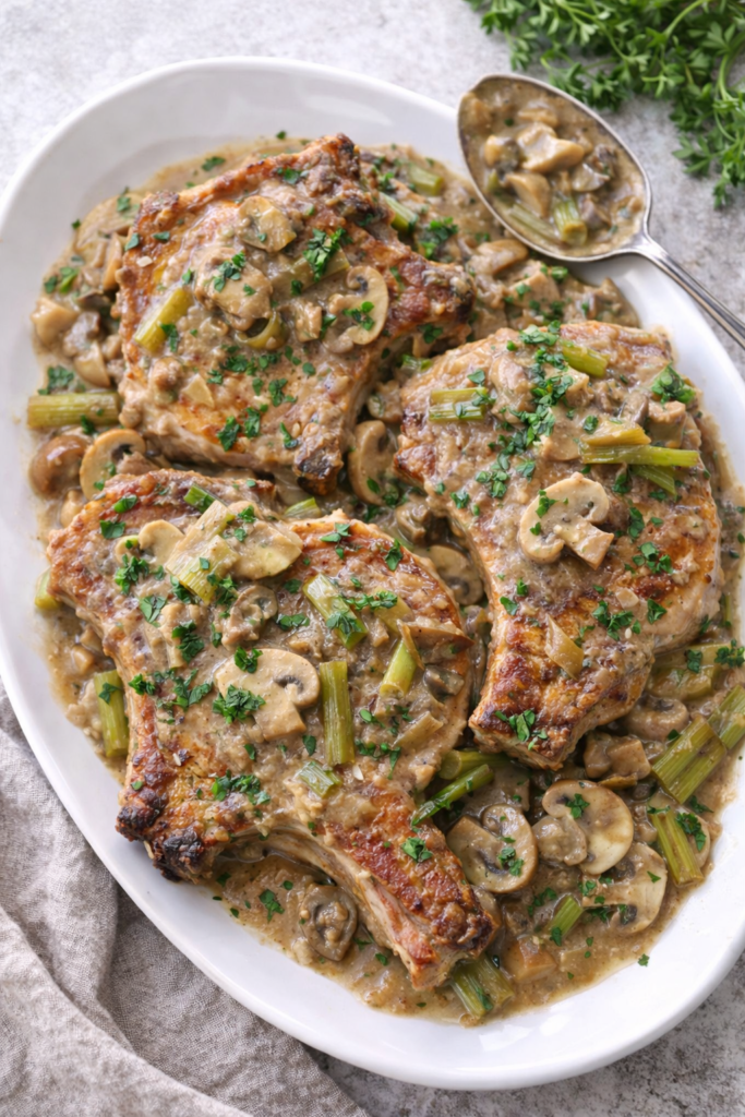 Pork chops served on a white platter with creamy mushroom and onion gravy spooned over the top