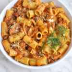 Creamy Italian sausage rigatoni with tender fennel, onions, and Pecorino Romano in a white bowl.