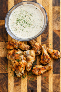 creamy alabama white bbq sauce in bowl with grilled chicken wings on cutting board