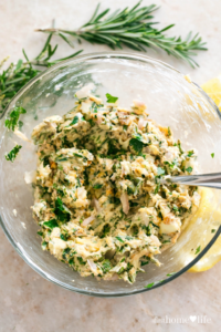 Fresh herb compound butter for poultry made with rosemary, parsley, garlic, and lemon in a glass bowl, ready to spread on chicken or turkey.