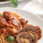 Italian braciole stuffed beef rolls in tomato sauce served with spaghetti on a white plate