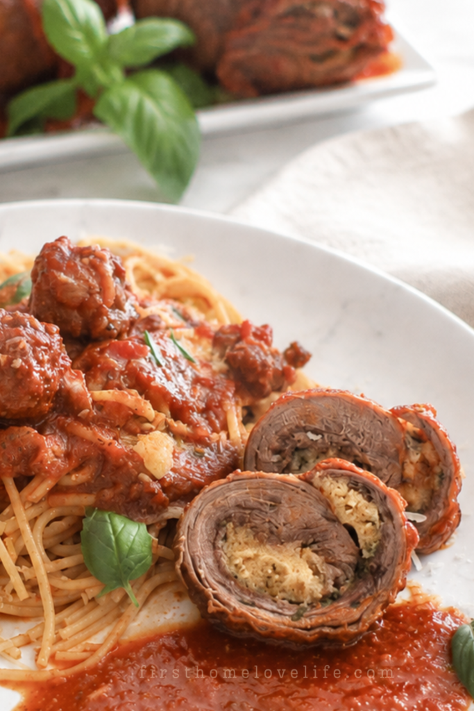 Italian braciole stuffed beef rolls in tomato sauce served with spaghetti on a white plate