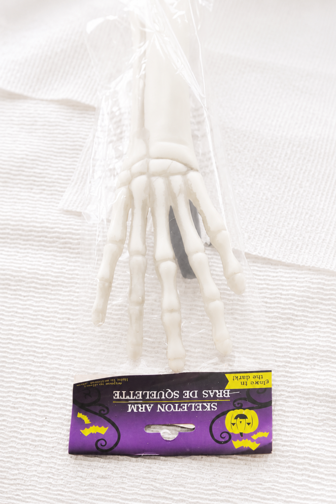 Dollar Tree skeleton arm package displayed on a white textured cloth before being transformed into Halloween wall decor.